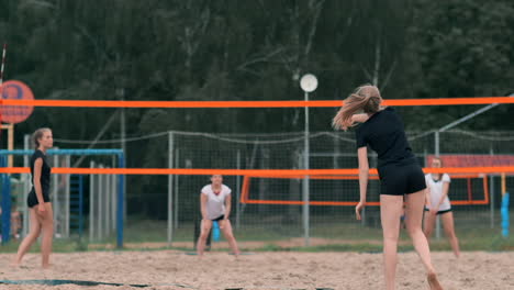 Junge-Frau-Spielt-In-Einer-Mannschaft-Volleyball-Am-Strand-Und-Führt-Einen-Angriff-Durch,-Indem-Sie-Den-Ball-Schlägt.-Mädchen-Schlägt-In-Zeitlupe-Den-Ball-Und-Führt-Einen-Angriff-Durch-Das-Netz-Aus.